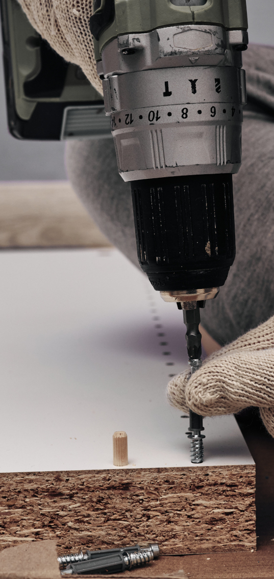 Un déménageur se sert d'un outil électrique pour démonter un meuble